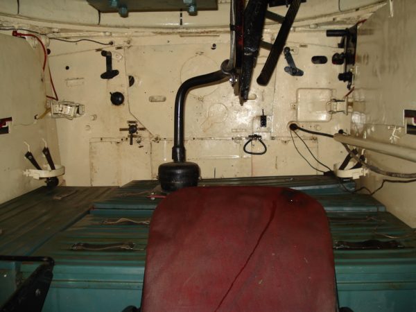 Interior of a T-34-85 viewed from the driver’s hatch, showing the ammunition boxes on which the loader had to stand in the absence of a turret basket. In the foreground is the driver’s seat. Levers for radiator flaps can be seen on the firewall. Balcer – CC BY 2.5