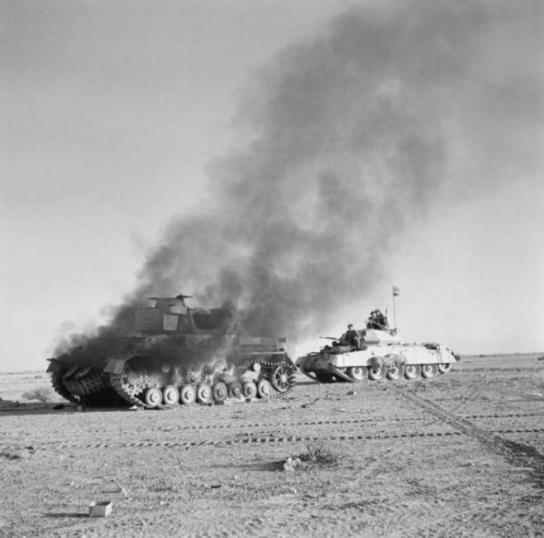 A British Crusader tank passing a burning German Panzer IV during Operation Crusader, late 1941.